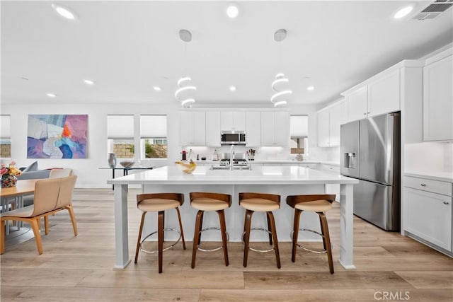 kitchen featuring appliances with stainless steel finishes, light wood-type flooring, light countertops, and white cabinetry