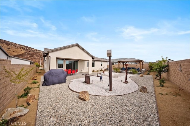 back of house featuring a patio area, a fenced backyard, a gazebo, and stucco siding