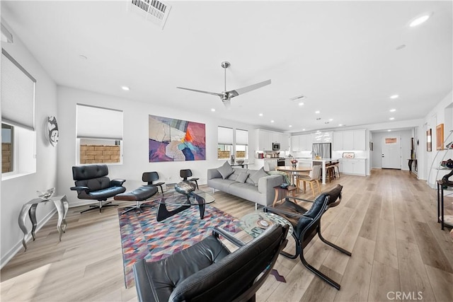 living room with ceiling fan and light hardwood / wood-style flooring