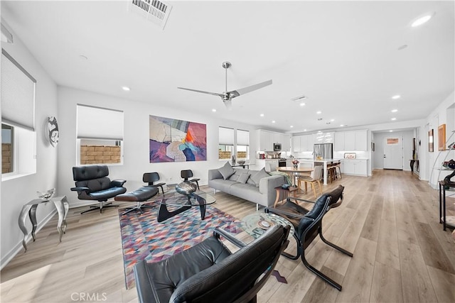 living room featuring light wood finished floors, baseboards, visible vents, and recessed lighting