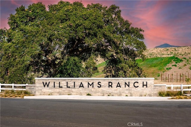 community / neighborhood sign with fence and a mountain view