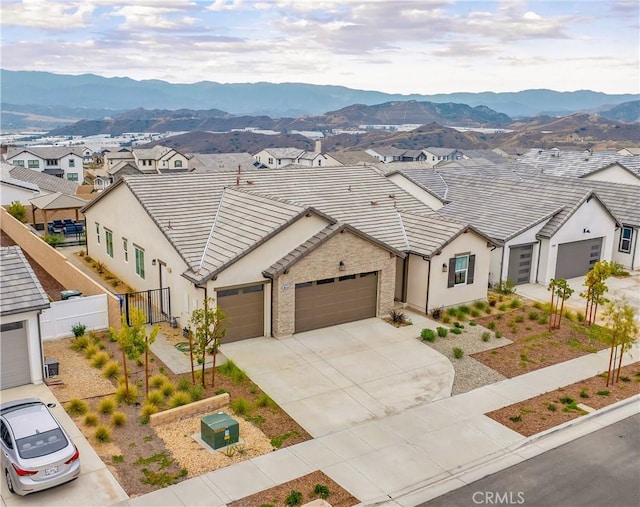 view of front facade featuring a residential view, fence, an attached garage, and a mountain view