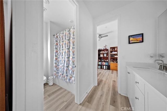 full bathroom with toilet, a ceiling fan, vanity, wood finished floors, and baseboards