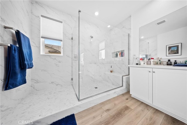 full bathroom with a marble finish shower, recessed lighting, visible vents, vanity, and wood finished floors