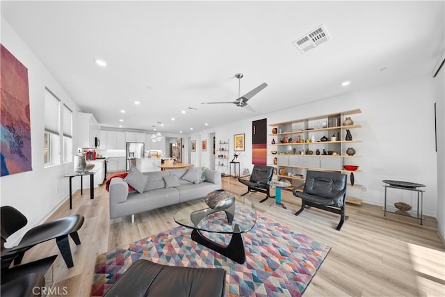 living room with light wood-style flooring, visible vents, ceiling fan, and recessed lighting