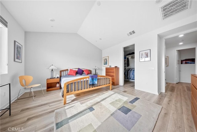 bedroom featuring lofted ceiling, light wood-style flooring, a spacious closet, and visible vents