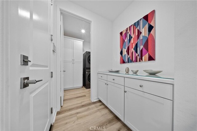 hall featuring light wood-type flooring and stacked washer / dryer