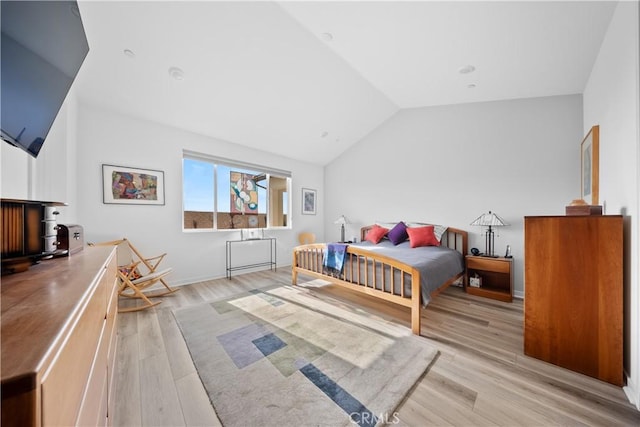 bedroom featuring lofted ceiling, baseboards, and light wood-style floors