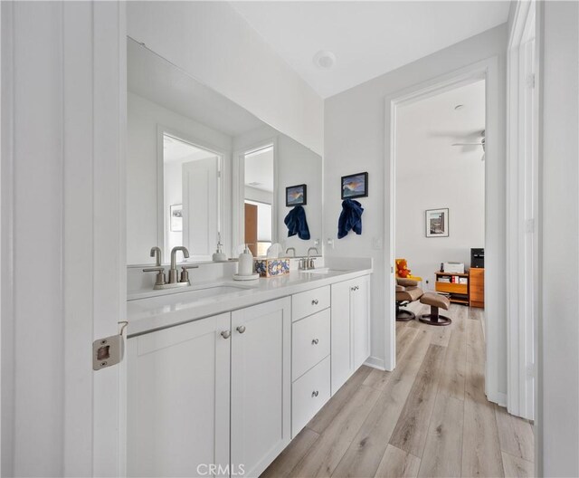 bar featuring white cabinetry, sink, and light hardwood / wood-style flooring