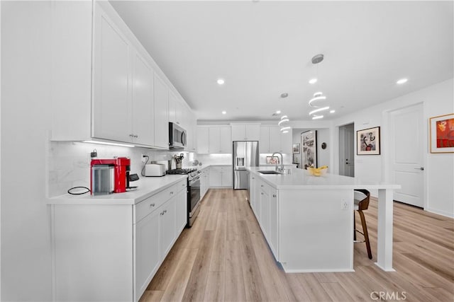 kitchen featuring light wood finished floors, white cabinetry, stainless steel appliances, and a sink