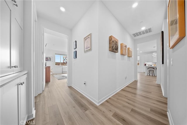 corridor with light wood finished floors, baseboards, visible vents, and recessed lighting