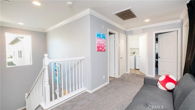 hallway with light carpet, ornamental molding, and washer and dryer