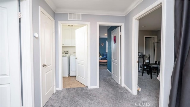 hall with light carpet, crown molding, and separate washer and dryer