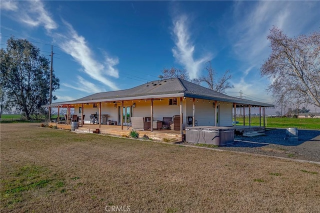 rear view of house with a patio, a yard, and a hot tub