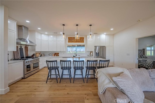 kitchen featuring pendant lighting, white cabinetry, premium appliances, and wall chimney exhaust hood