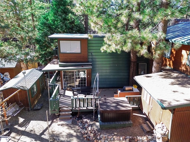 rear view of house with a deck and a jacuzzi