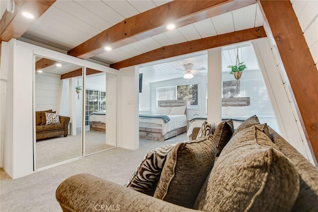 carpeted bedroom with ceiling fan and beamed ceiling