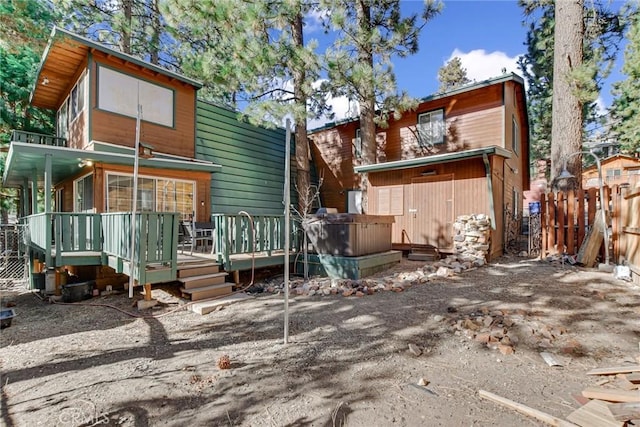 back of property with a deck and a hot tub