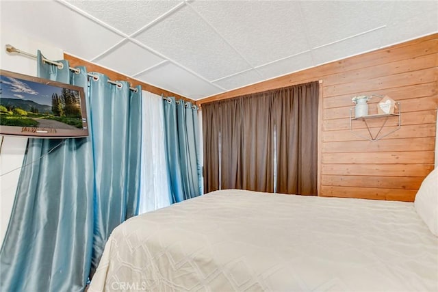 bedroom with a paneled ceiling and wooden walls