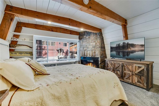 carpeted bedroom with a stone fireplace, wood walls, and beamed ceiling