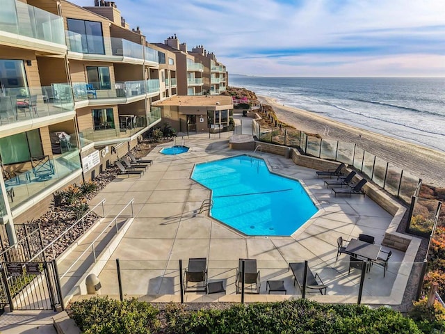 view of pool featuring a beach view, a water view, and a patio