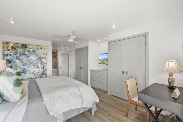 bedroom featuring ceiling fan, two closets, connected bathroom, and light wood-type flooring