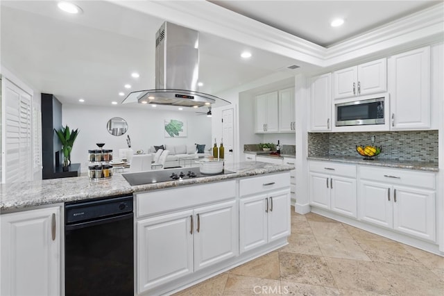 kitchen featuring stainless steel microwave, white cabinetry, tasteful backsplash, island exhaust hood, and black electric cooktop