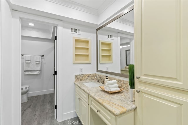 bathroom featuring vanity, toilet, built in features, hardwood / wood-style flooring, and crown molding