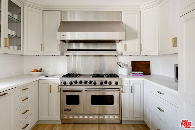 kitchen with light hardwood / wood-style floors, backsplash, range with two ovens, and wall chimney exhaust hood