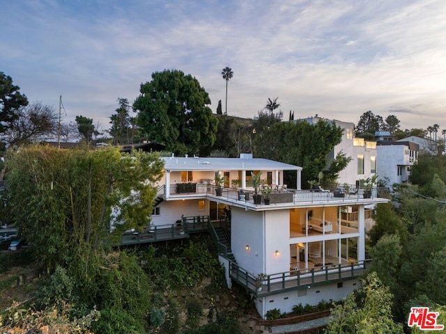 back house at dusk featuring a balcony