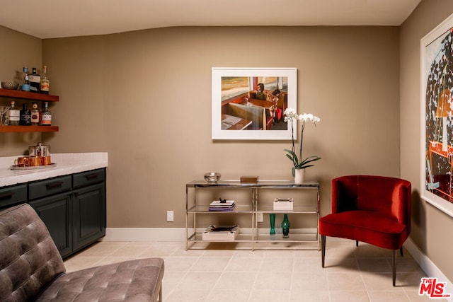 living area featuring light tile patterned floors and bar