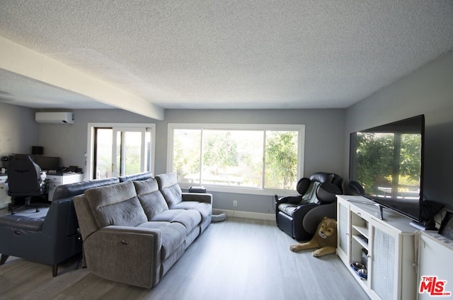 living room with a textured ceiling, light hardwood / wood-style flooring, and an AC wall unit