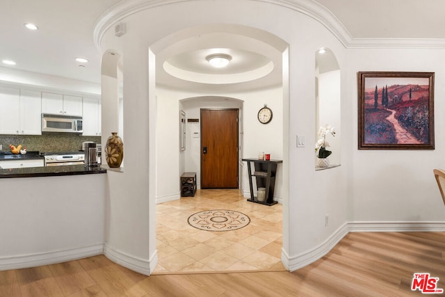 corridor with crown molding and light tile patterned floors