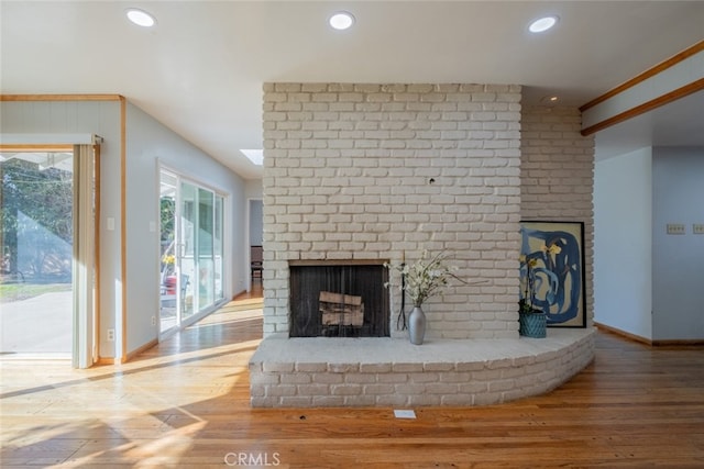 unfurnished living room featuring hardwood / wood-style flooring and a brick fireplace