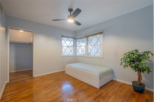 bedroom featuring light hardwood / wood-style flooring, a closet, ceiling fan, and a walk in closet