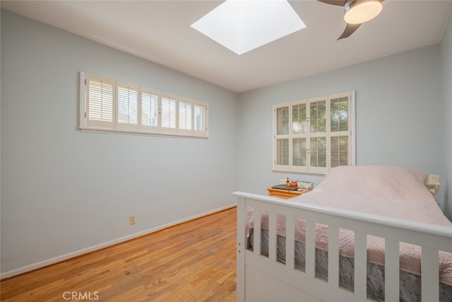 bedroom with ceiling fan, hardwood / wood-style flooring, and a skylight