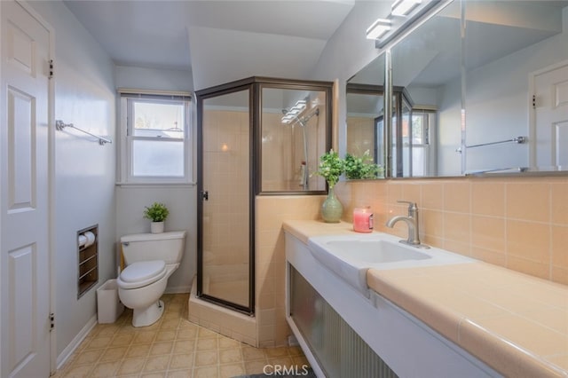 bathroom with toilet, a shower with door, vanity, and tasteful backsplash