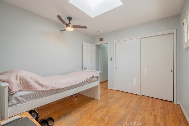 bedroom featuring a closet, a skylight, ceiling fan, and light wood-type flooring