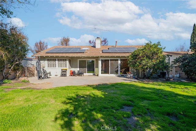 back of house with a lawn, solar panels, and a patio