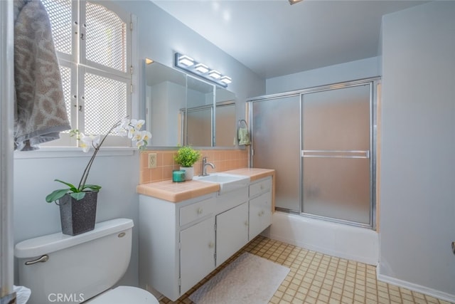 full bathroom with vanity, toilet, bath / shower combo with glass door, and tasteful backsplash