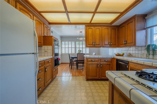 kitchen featuring black appliances, backsplash, and tile counters