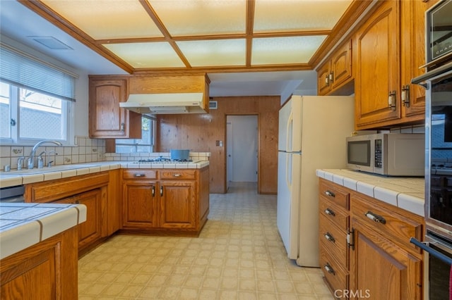 kitchen featuring tile counters, decorative backsplash, sink, gas cooktop, and white refrigerator