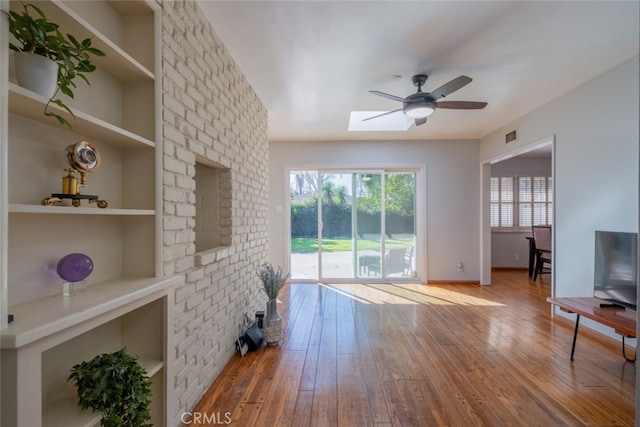 living room featuring built in features, light wood-type flooring, and ceiling fan