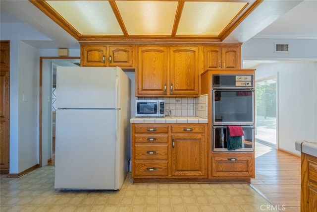 kitchen with tile countertops, white refrigerator, tasteful backsplash, and double oven