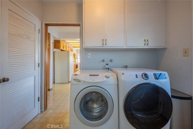 clothes washing area featuring separate washer and dryer and cabinets