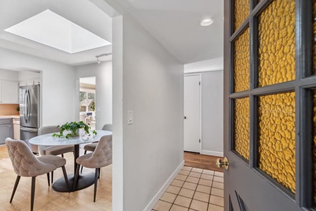 hallway with light tile patterned floors and a skylight