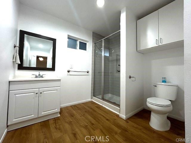 bathroom featuring hardwood / wood-style flooring, toilet, an enclosed shower, and vanity