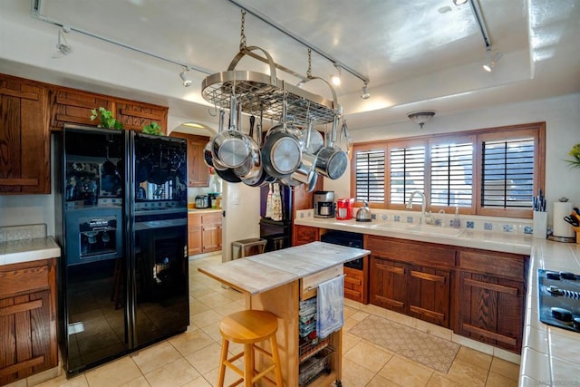 kitchen with black fridge, sink, light tile patterned floors, and a kitchen bar