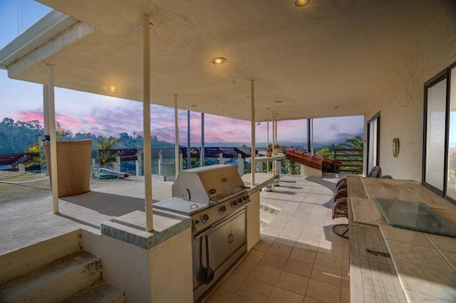 patio terrace at dusk featuring area for grilling