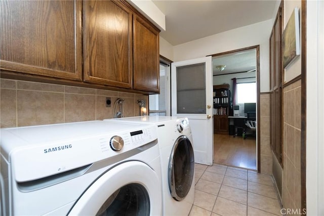 laundry room with washing machine and clothes dryer, cabinets, and light tile patterned flooring